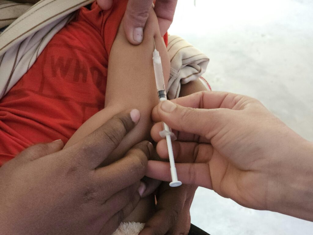 A child getting a vaccination shot administered by a healthcare professional indoors.